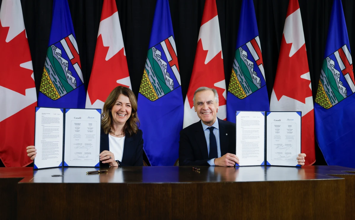Prime Minister Mark Carney, right, signs an MOU with Alberta Premier Danielle Smith in Calgary, Alta - Photo: Jeff McIntosh /The Canadian Press via AP