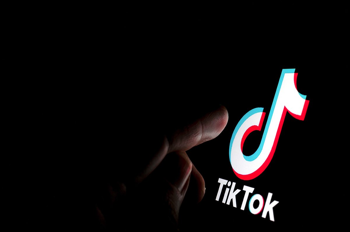 TikTok app logo on the screen and a finger about to touch it - Photo: Stone / UK